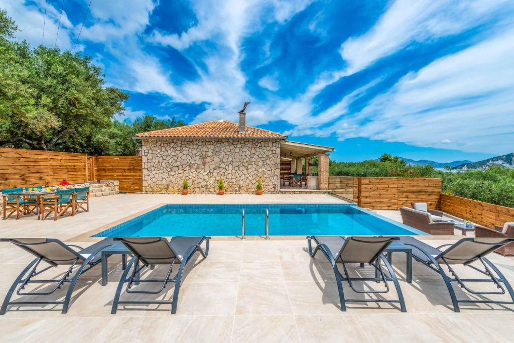 a pool with chairs and a table and a house at Villa Marathias in Marathias