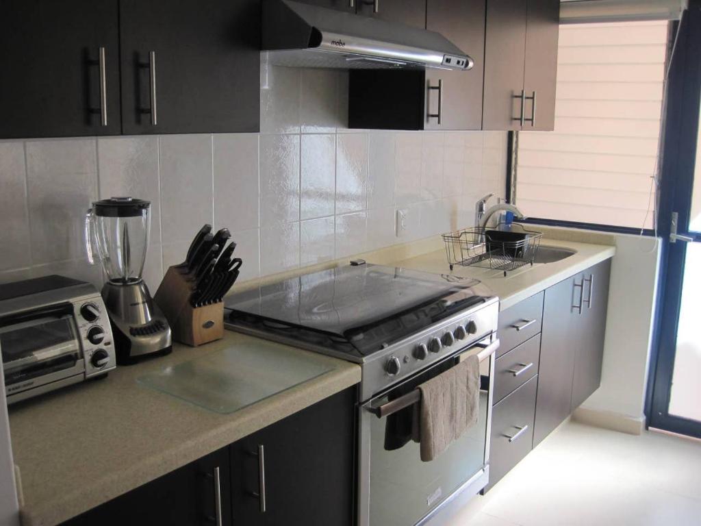 uma cozinha com um lavatório e um fogão forno superior em Linda y Acogedora Suite Áreas verdes Alberca Zona Norte 27B em Mendiola