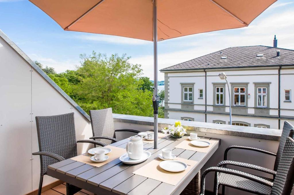 a table and chairs on a balcony with an umbrella at Haus Behr am See in Radolfzell am Bodensee