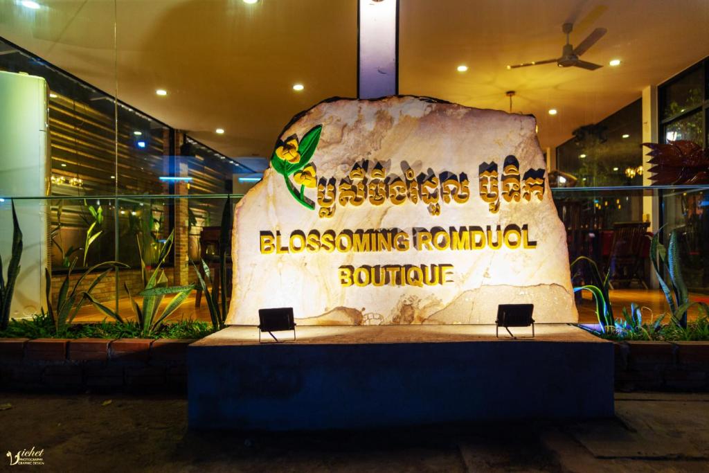 a sign for a restaurant with a large rock at Blossoming Romduol Boutique in Siem Reap