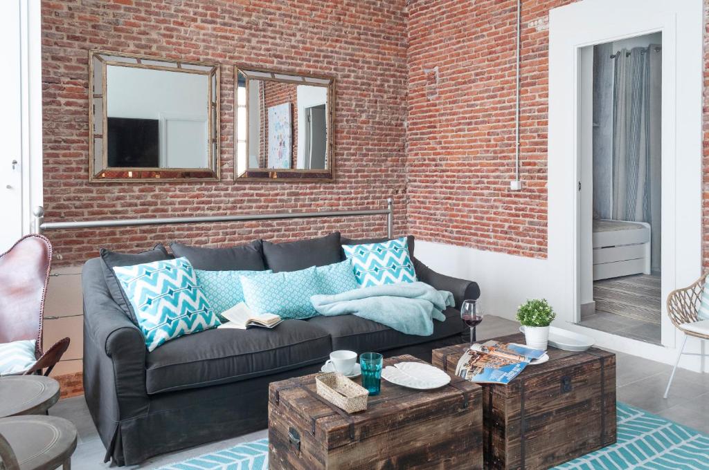 uma sala de estar com um sofá e uma parede de tijolos em Cosy Apartment in the heart of Barrio de las Letras em Madri