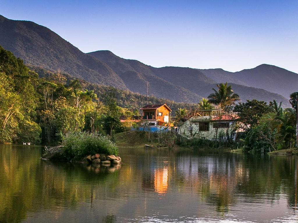a house on a river with mountains in the background at Lagamar Ecohotel in Cananéia