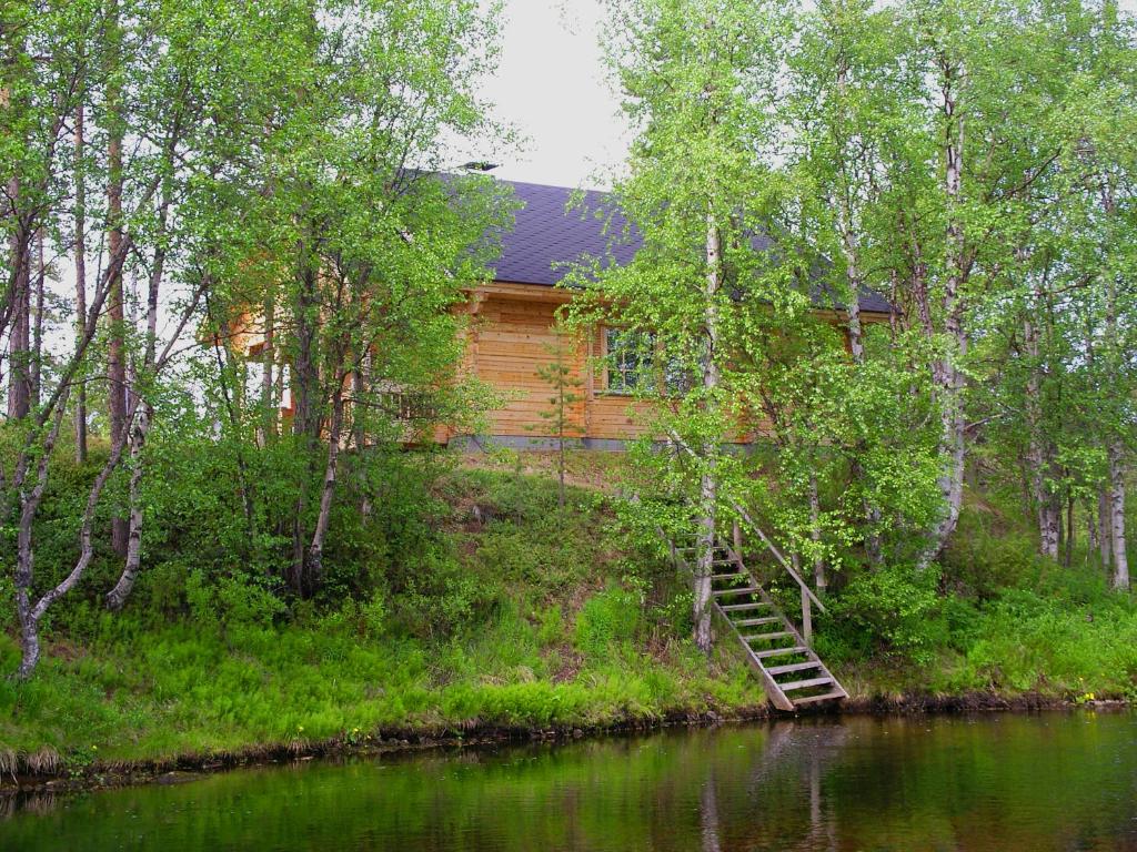 Ounasloma Luxury Cottages في Enontekiö: كابينة خشب في الغابة بجوار نهر