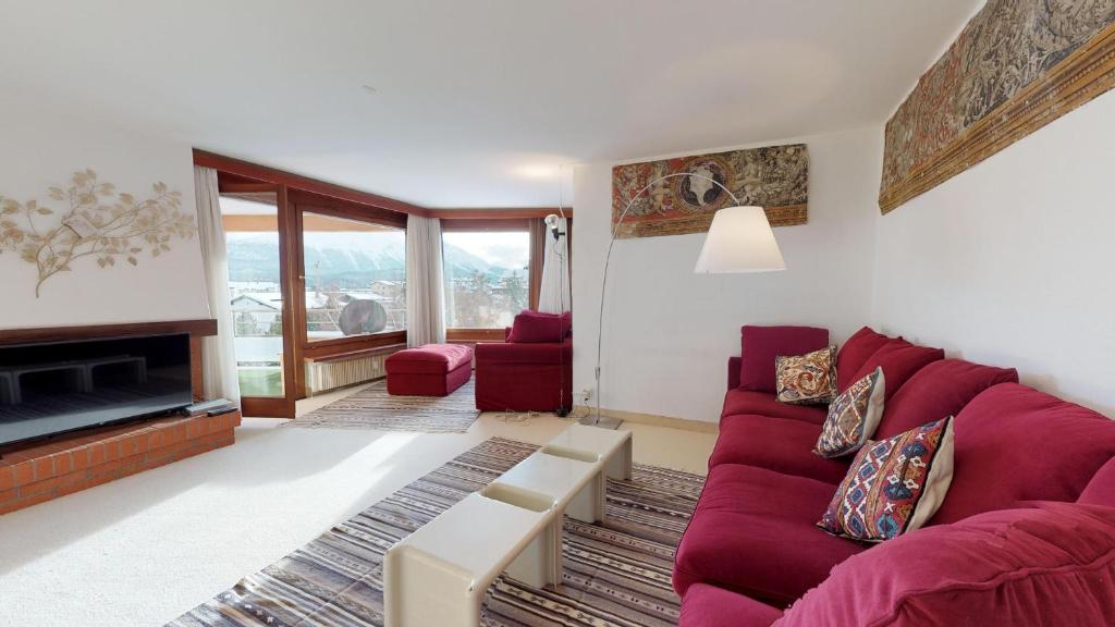 a living room with a red couch and a fireplace at Abitaziun Quadratscha 22 - Samedan in Samedan