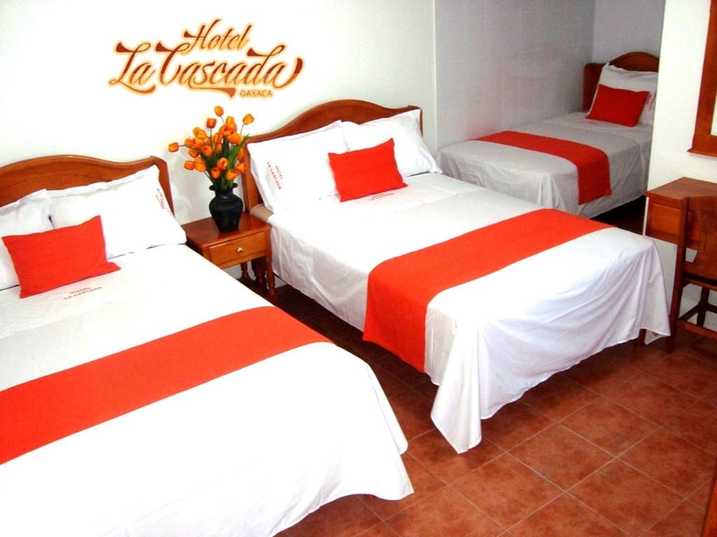 a hotel room with two beds with red and white sheets at Hotel La Cascada in Oaxaca City