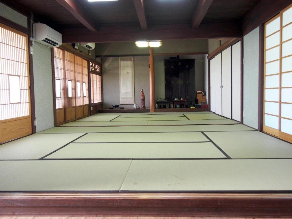 an empty room with white floors and windows at 古民家民宿 麻の宿 in Kotohira