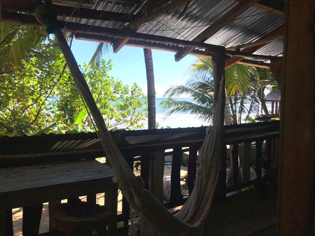 a hammock on a porch with a palm tree at Surfhost in Garza