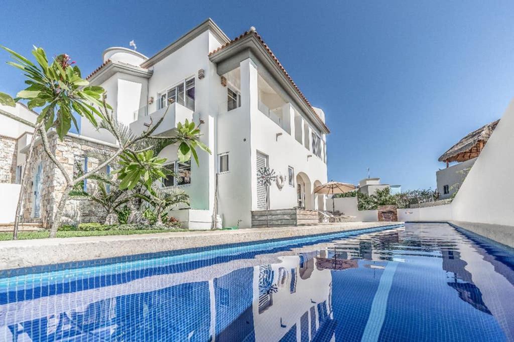 a white house with a swimming pool in front of it at Casa Santosha in Isla Mujeres