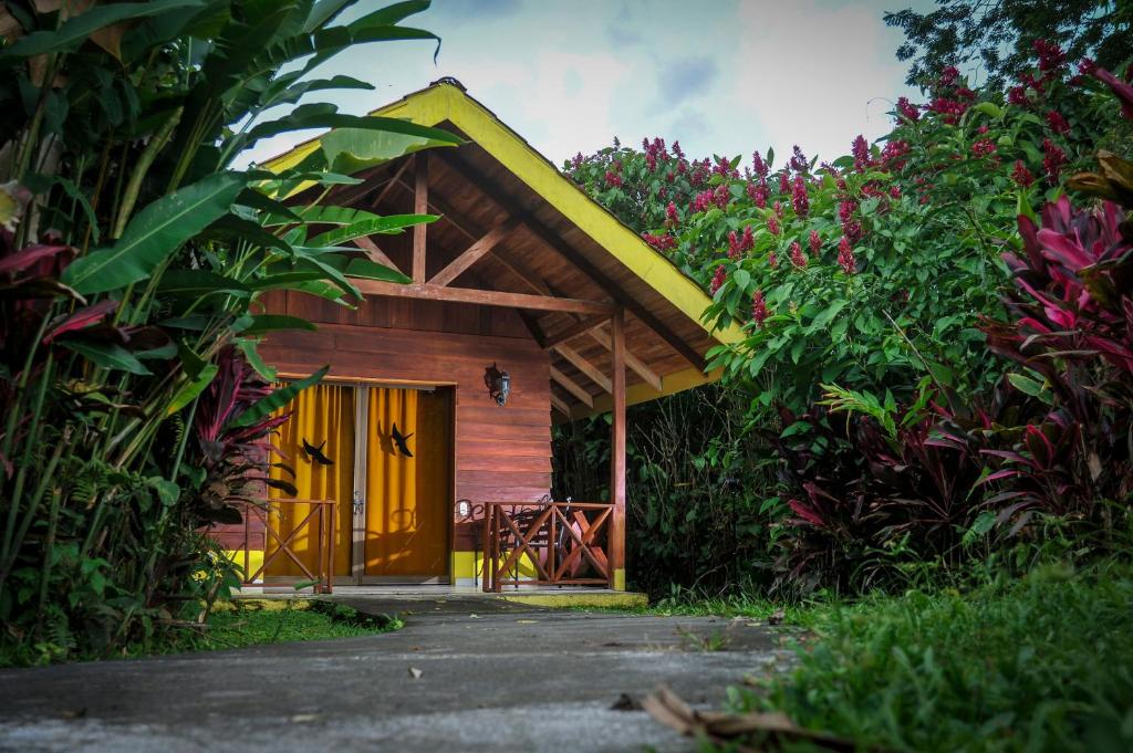 a wooden cabin with a yellow door in a garden at Selvita Lodge Arenal in Fortuna