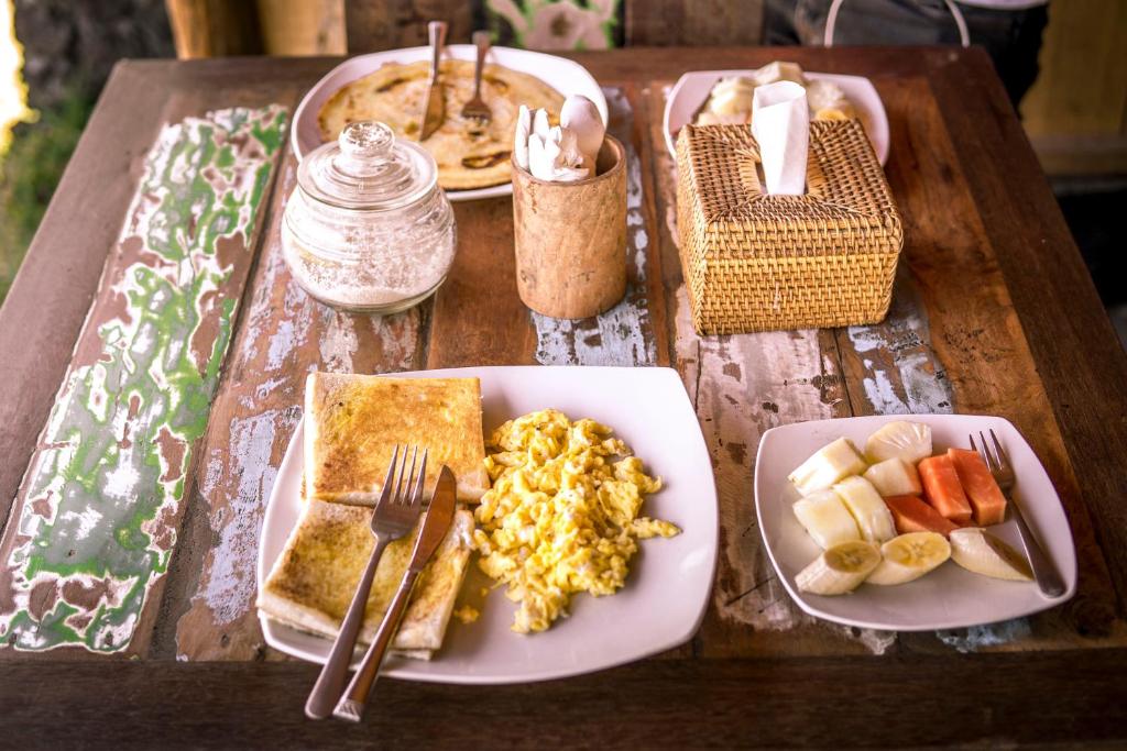 een houten tafel met borden eten erop bij Black Lava Hostel and Lodge in Kintamani