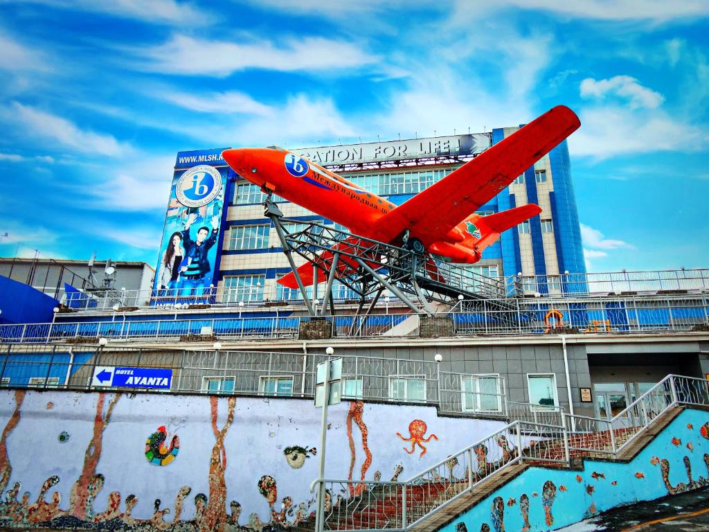 Um avião vermelho está a sobrevoar um edifício. em Uchebnaya Hotel em Vladivostok