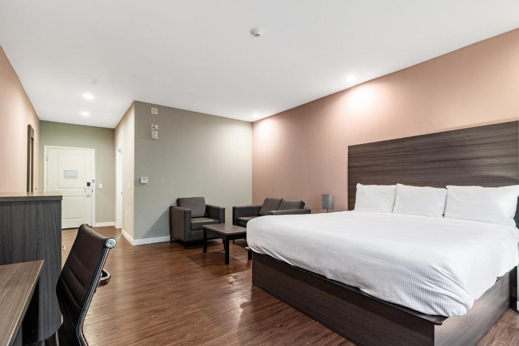 um quarto de hotel com uma cama, uma mesa e cadeiras em Scottish Inns & Suites Houston, TX em Houston