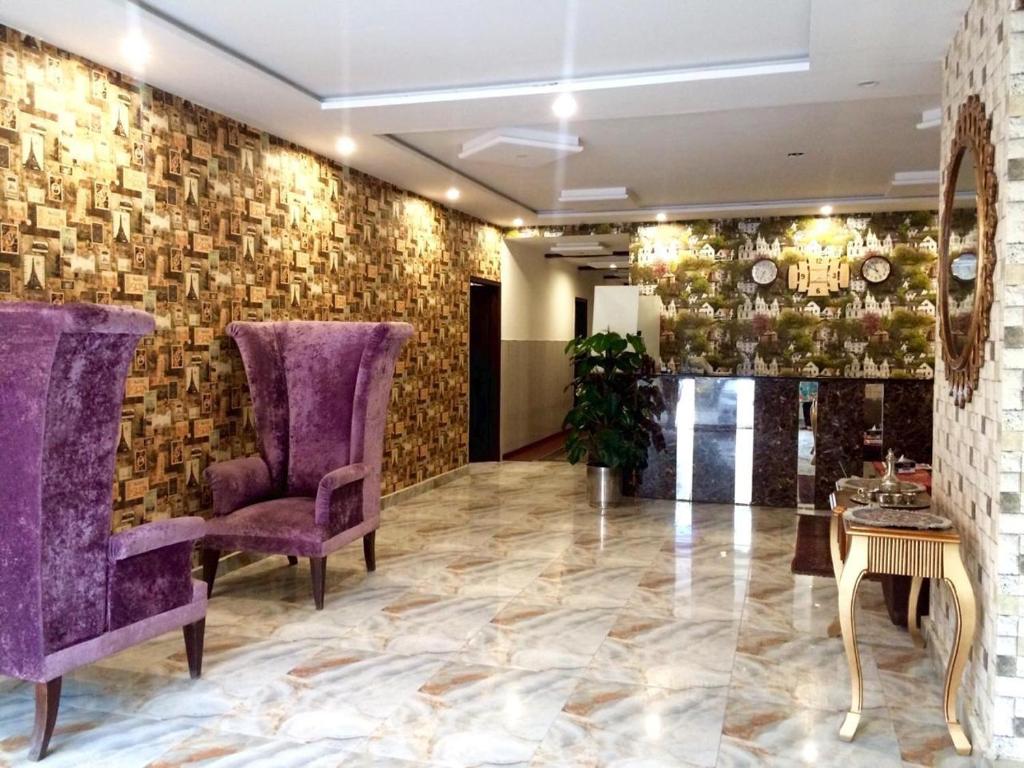 a lobby with purple chairs and a brick wall at Hotel Premier Inn Johar Town Lahore in Lahore