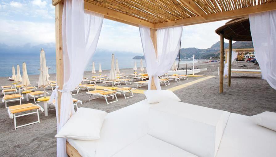een slaapkamer met witte bedden en stoelen op het strand bij Hotel Sylesia in Letojanni