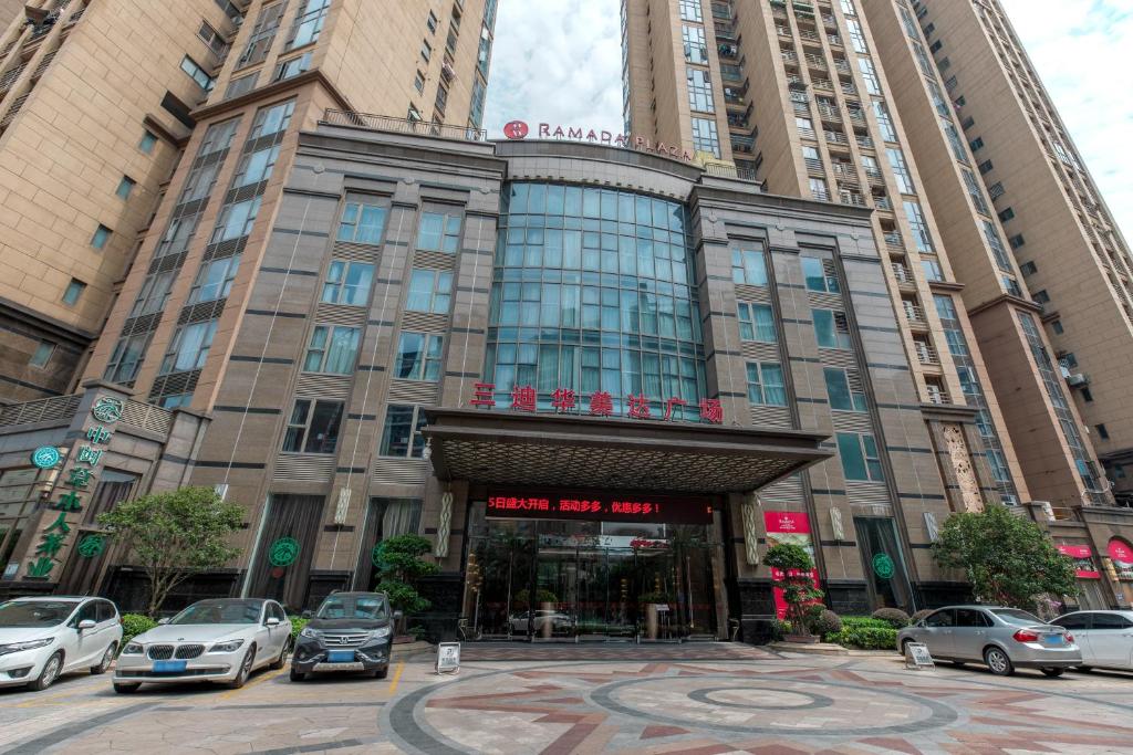 a large building with cars parked in front of it at Ramada Plaza By Wyndham Fuzhou South in Fuzhou