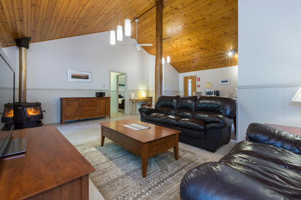 a living room with a leather couch and a coffee table at Bushy Lake Chalets in Margaret River Town