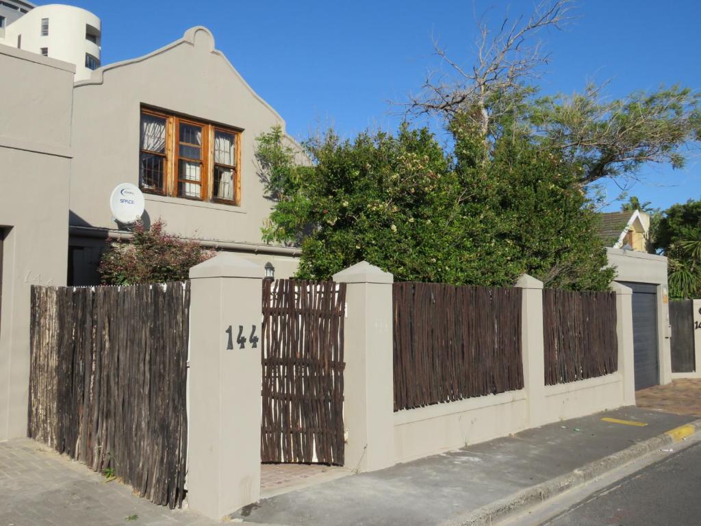 a white fence in front of a house at Winelands beach cottage in Cape Town