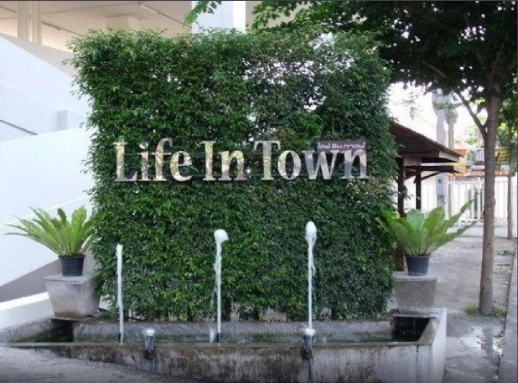 a green wall with the words life in town on it at Life In Town Chiangmai in Chiang Mai
