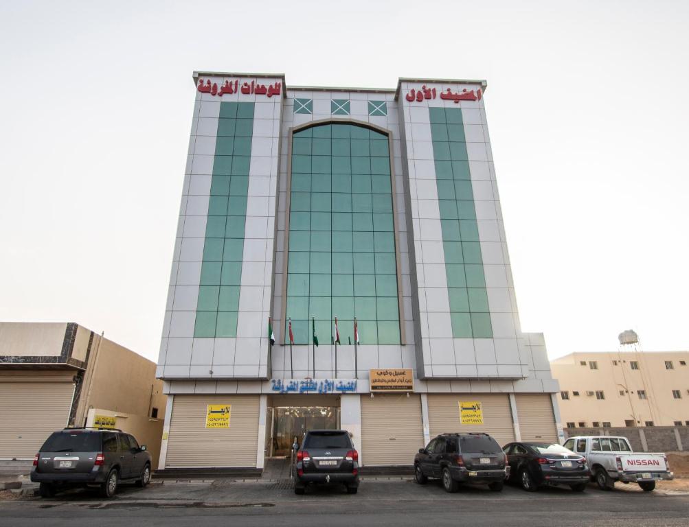 Waha AL Mudaif Serviced Apartments في تبوك: مبنى فيه سيارات متوقفة في موقف للسيارات