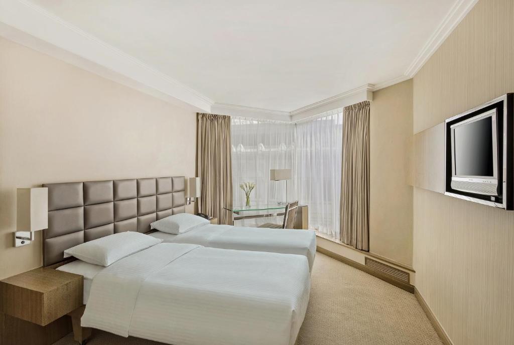 a hotel room with two beds and a television at The Kowloon Hotel in Hong Kong