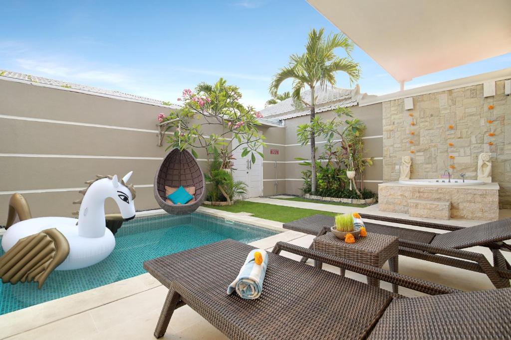 a backyard with a swimming pool with a white swan and a pool at Bali Cosy Villa Adults Only in Legian