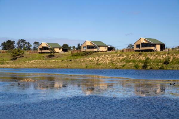 a group of houses on a hill next to a body of water at Wernich Landgoed in George