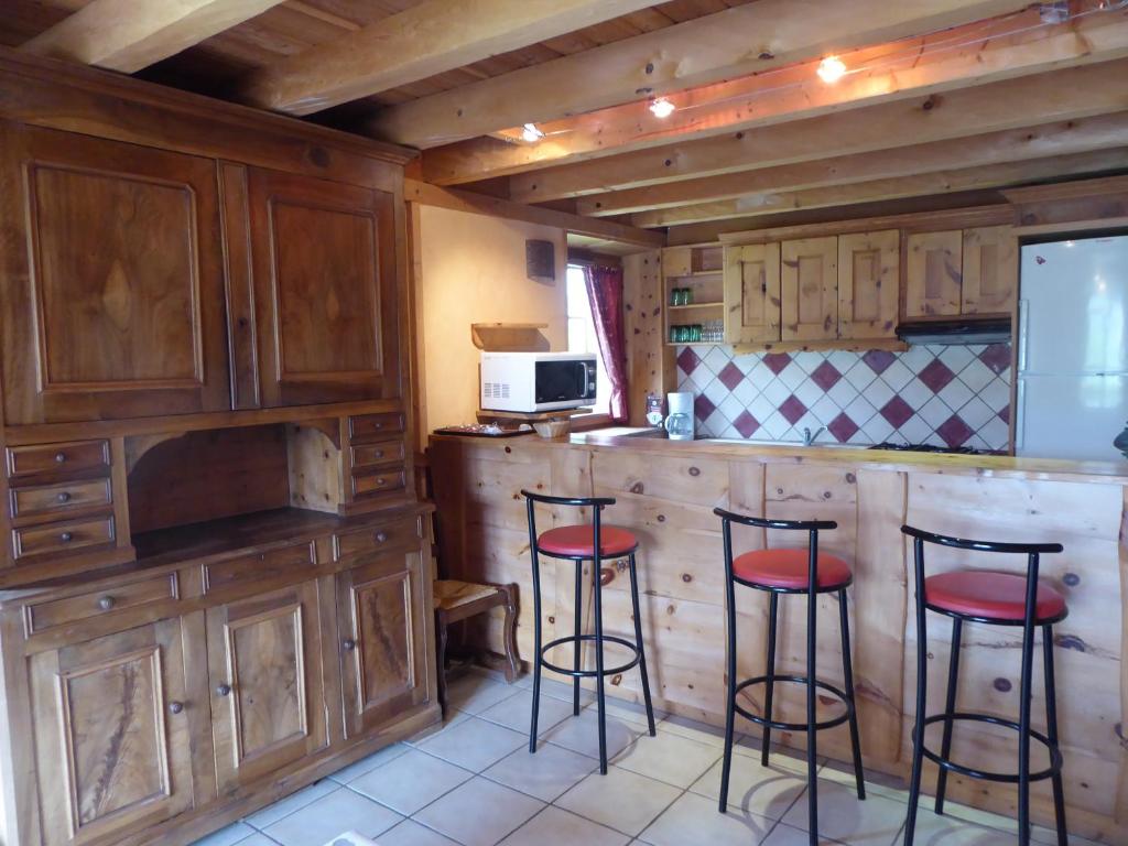 a kitchen with wooden cabinets and red bar stools at Chalet Les Liouès in Sollières-Sardières