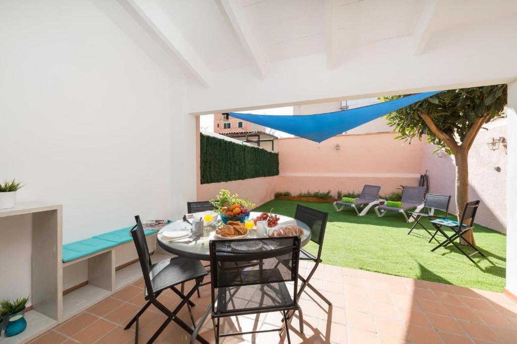 een patio met een tafel en stoelen en een tuin bij Ca na Rosa (Es Portitxol) in Palma de Mallorca