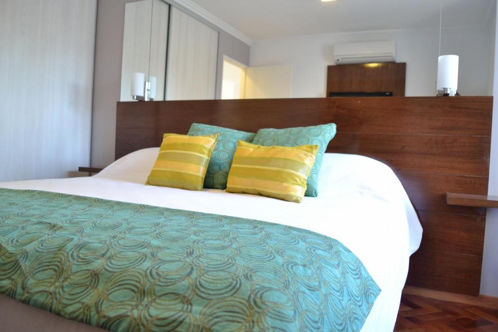 een slaapkamer met een bed met gele en blauwe kussens bij AT Suites in Cordoba