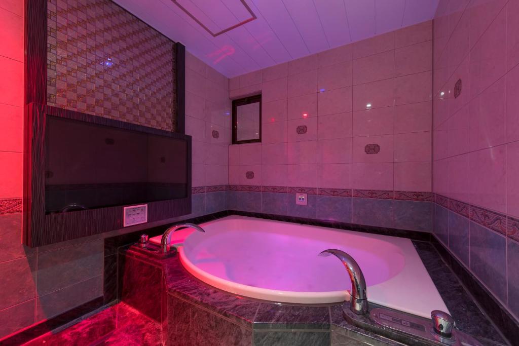 千葉的住宿－HOTEL W-AVANZA-W GROUP HOTELS and RESORTS-，粉红色的浴室设有落地花卉浴缸