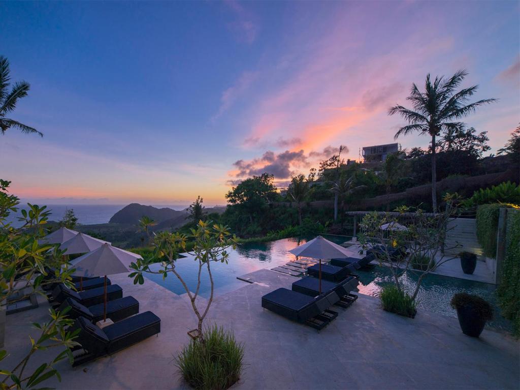 a pool with chairs and umbrellas at a resort at Selong Selo Resort and Residences in Selong Belanak
