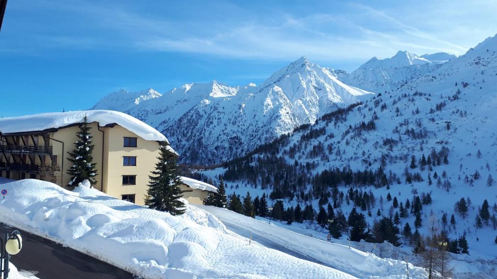 a building covered in snow with mountains in the background at Appartamento Presanella in Passo del Tonale