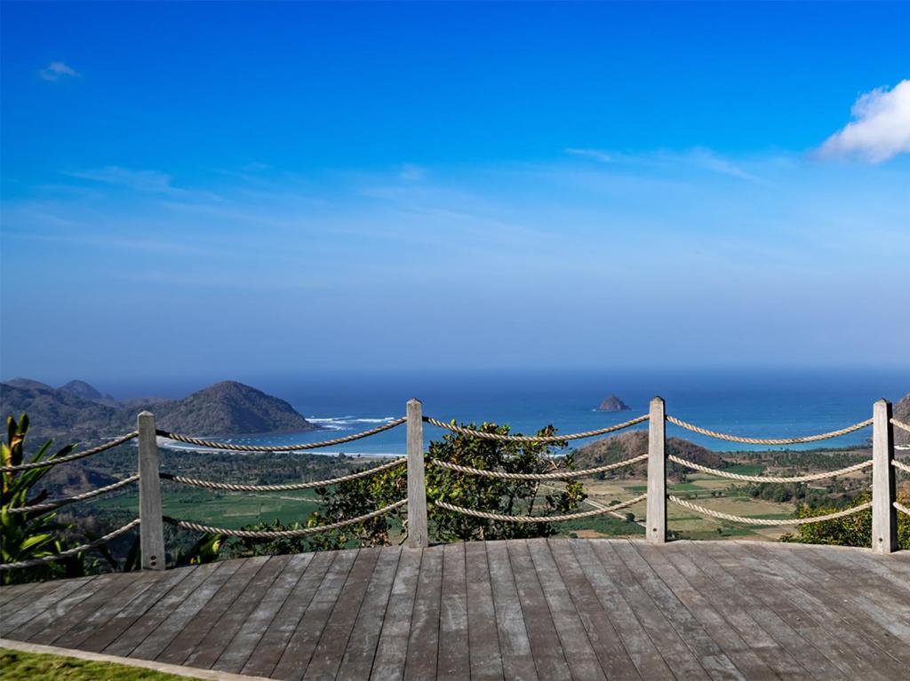 a wooden boardwalk with a view of the ocean at Selong Selo Resort and Residences in Selong Belanak