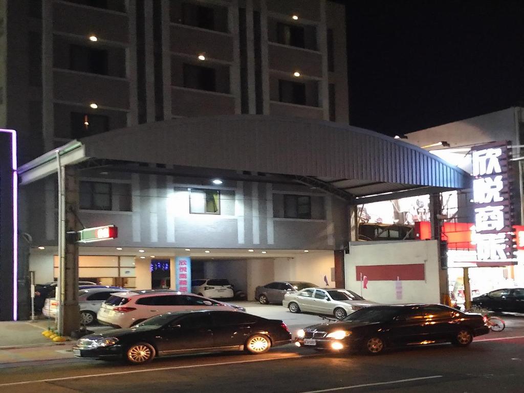 dos autos estacionados frente a una gasolinera por la noche en 欣悅商務旅店 en Toufen