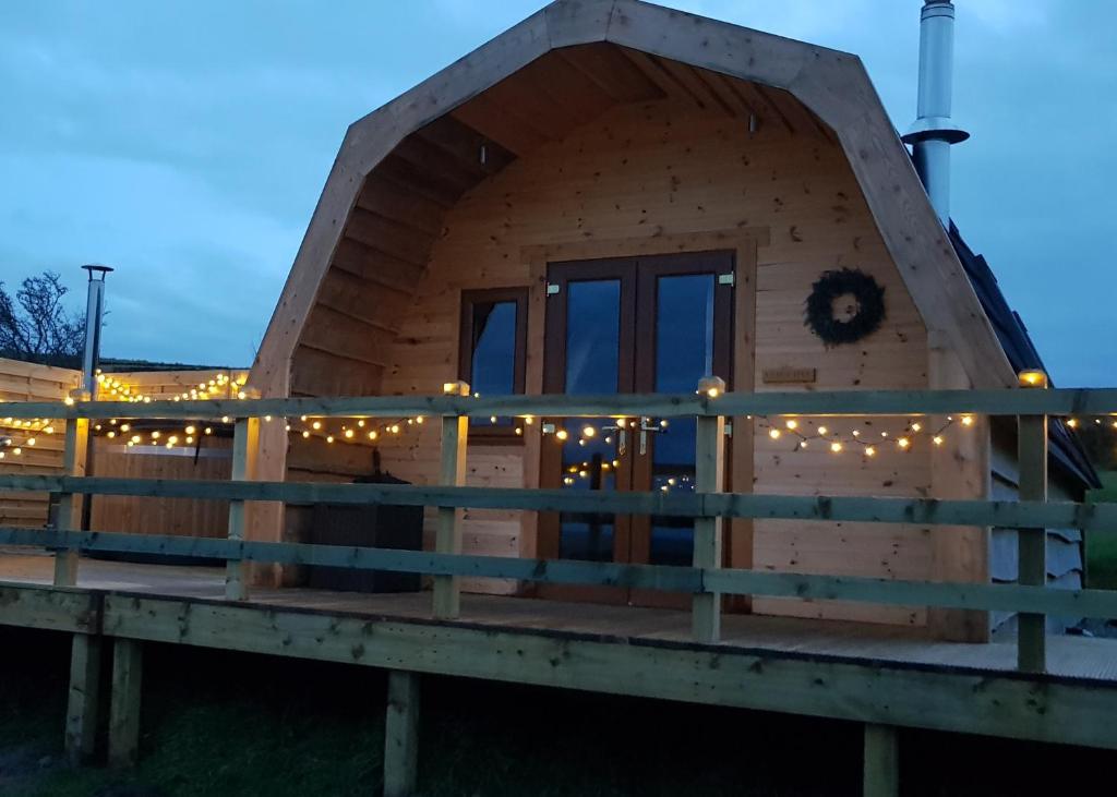 a log cabin with a porch at night at Panoramic Pods in Allendale Town