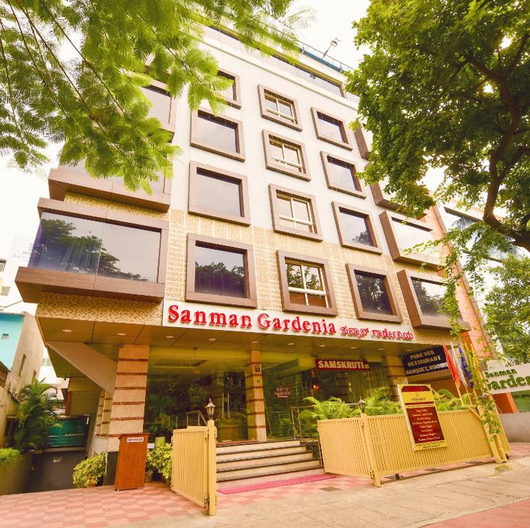 a large white building with a sign on it at Hotel Sanman Gardenia in Bangalore