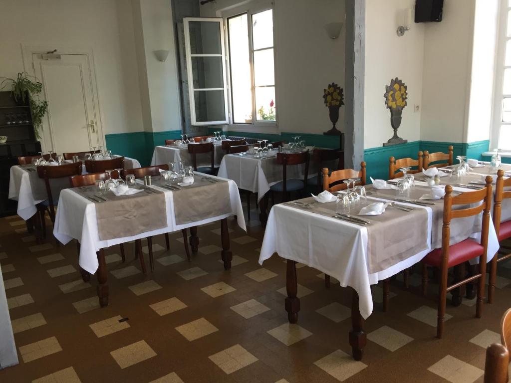 een eetkamer met tafels en stoelen met witte tafellakens bij Hôtel du Cygne in LʼAigle