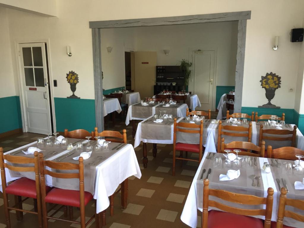 a restaurant with tables and chairs with white tablecloths at Hôtel du Cygne in LʼAigle