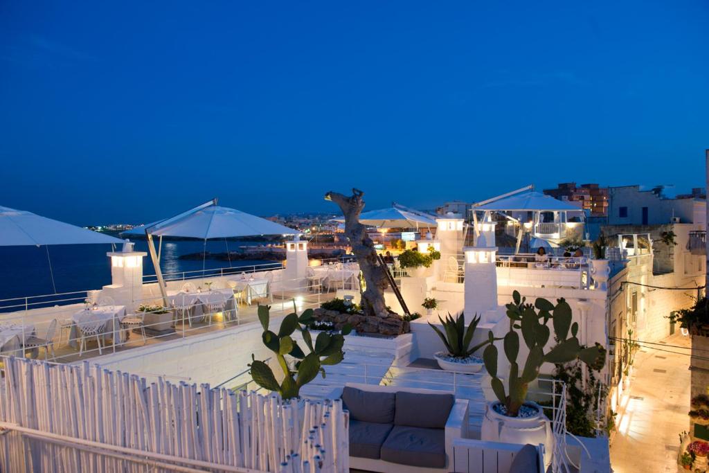 a patio with white furniture and cactuses at night at Hotel Don Ferrante in Monopoli