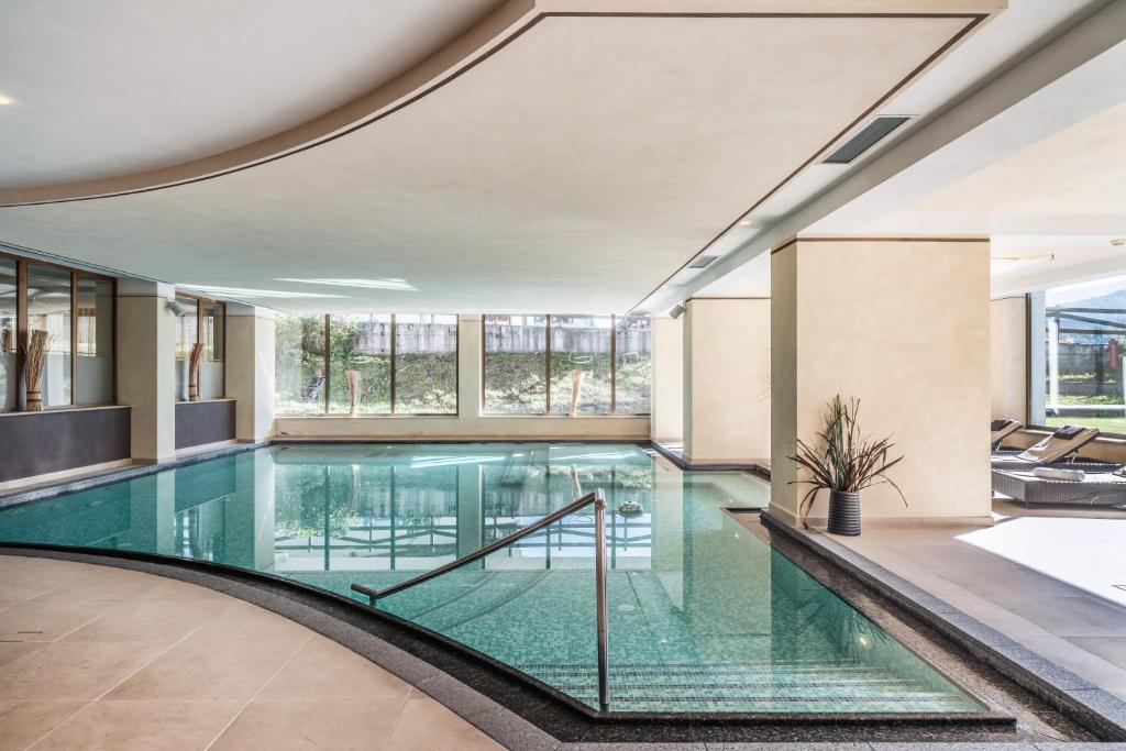 una piscina in un edificio con pavimenti e finestre in vetro di Residence Anda a Pozza di Fassa