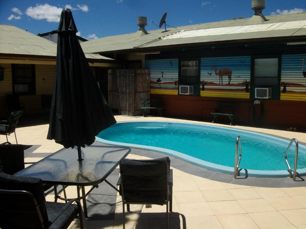 
a swimming pool with a chair and a towel rack at Broken Hill Tourist Lodge in Broken Hill
