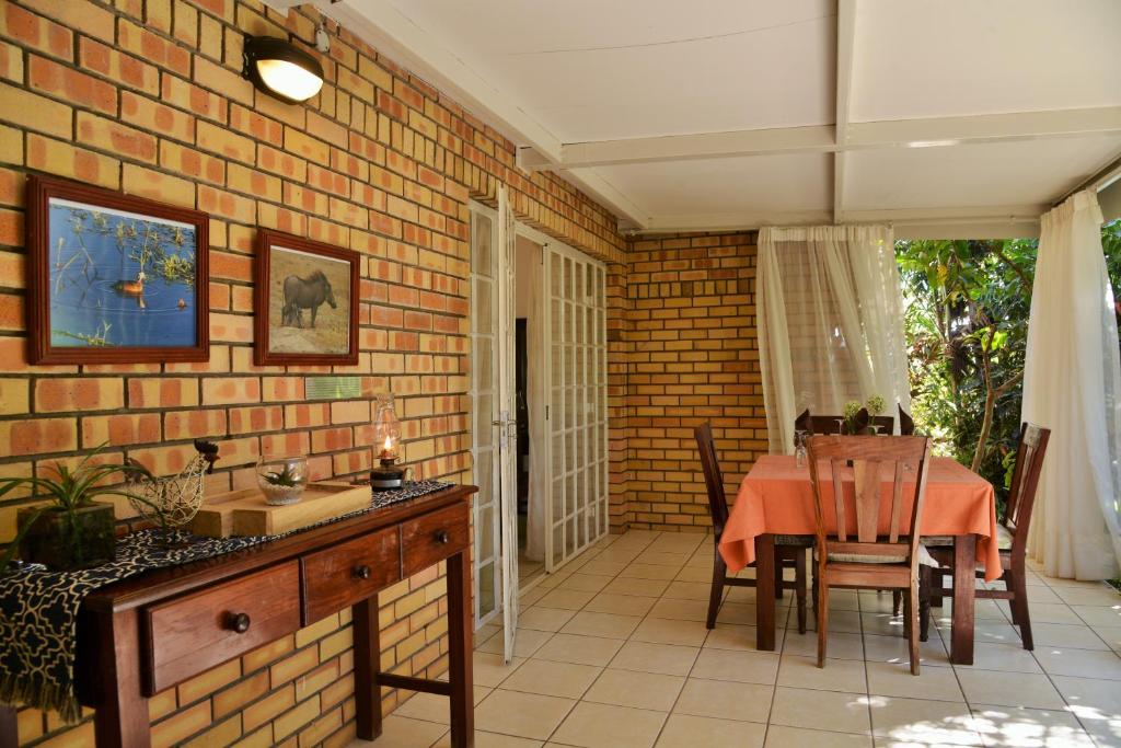 a dining room with a table and a brick wall at Chobe River Cottages in Kasane