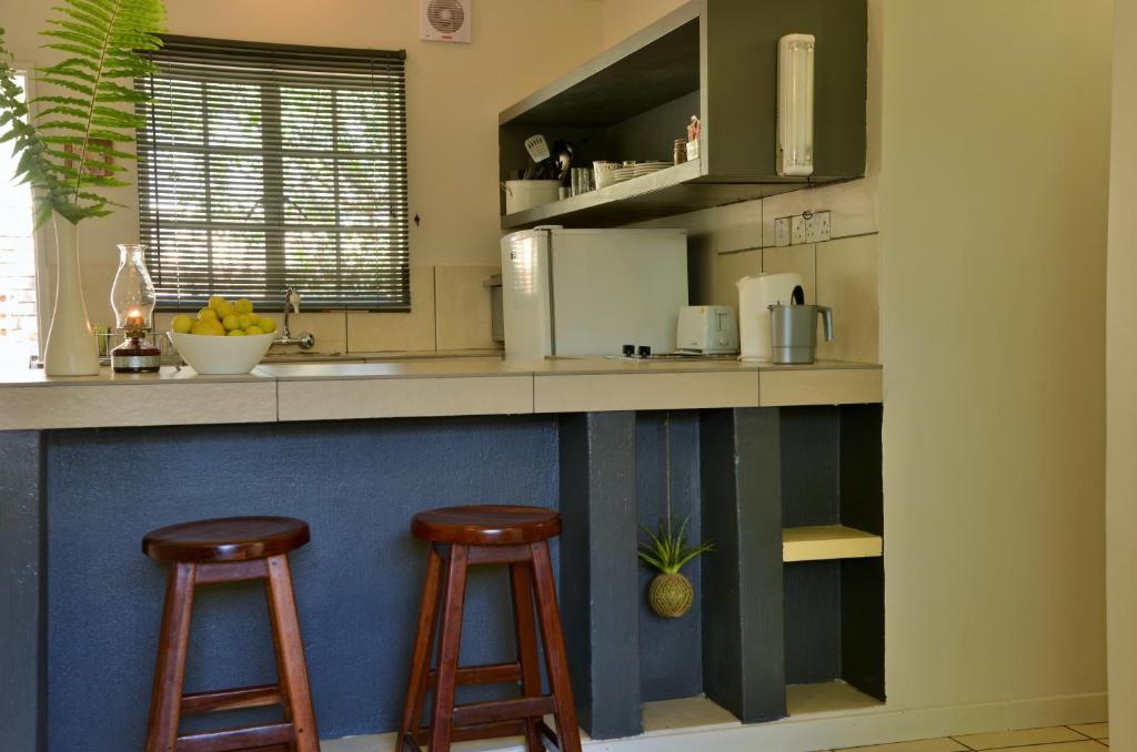 a kitchen with two bar stools and a counter top at Chobe River Cottages in Kasane