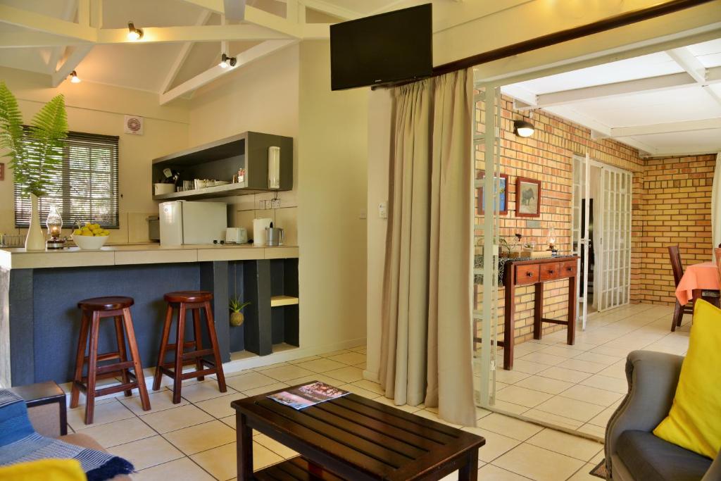 a living room and kitchen with a couch and a table at Chobe River Cottages in Kasane