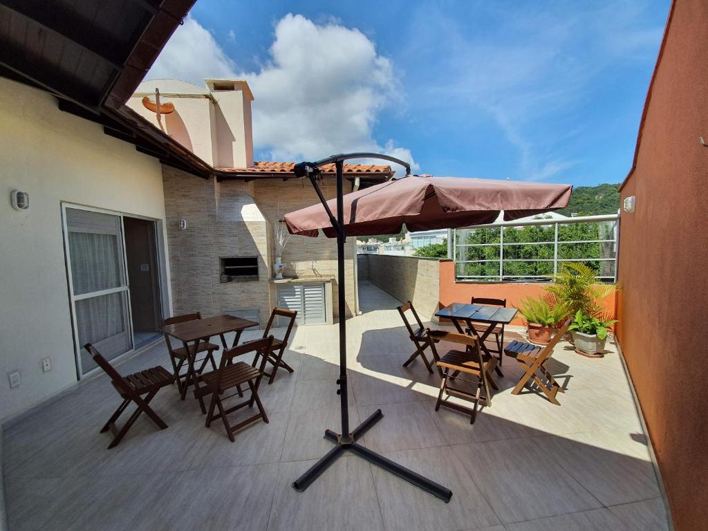 un patio con mesa, sillas y sombrilla en Linda cobertura INGLESES FLORIANOPOLIS, en Florianópolis