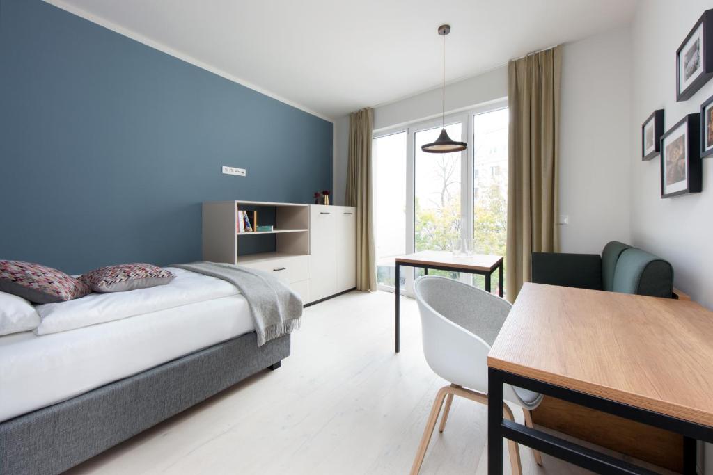 a bedroom with a bed and a desk and a table at Brera Serviced Apartments Leipzig in Leipzig
