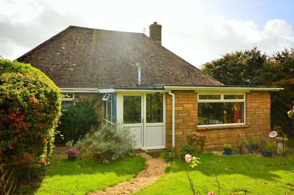 una pequeña casa de ladrillo con garaje blanco en Whitestones, en Brighstone