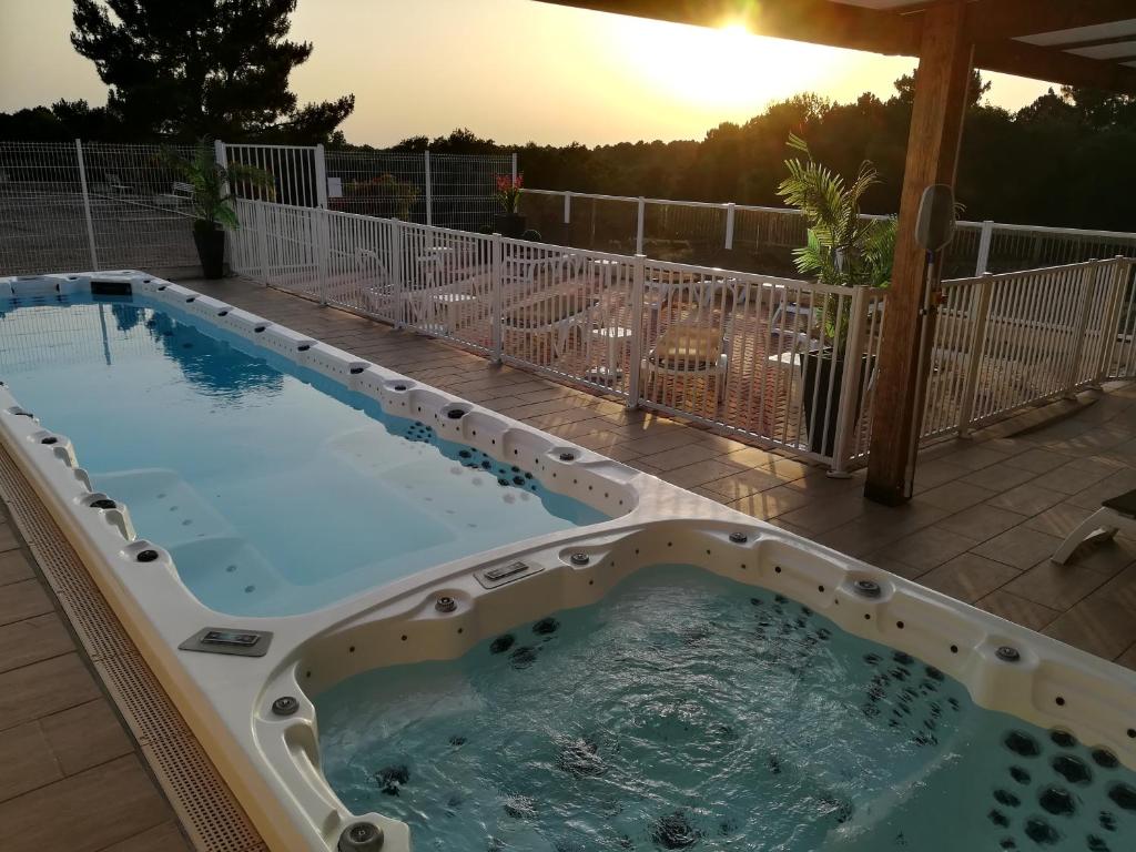 een hot tub op een patio met de zonsondergang op de achtergrond bij Hotel Restaurant Logis Le Tropicana in Douville