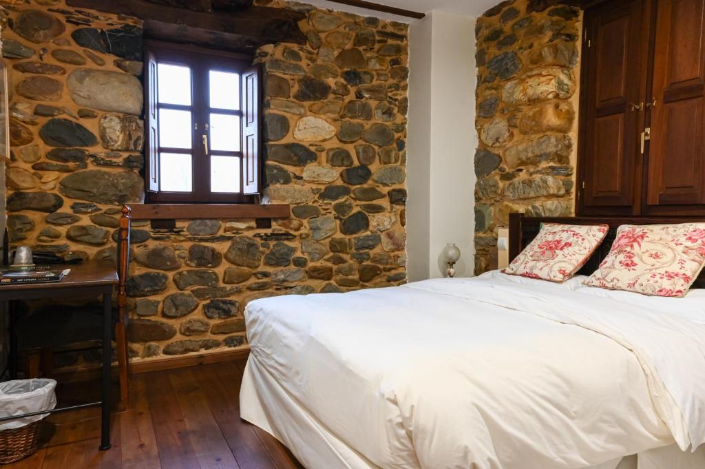 a bedroom with a stone wall with a bed and a window at Restaurante - Hotel La Tronera in Villadepalos