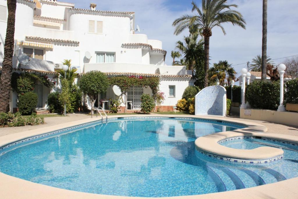 a swimming pool in front of a large white house at Apartamento Oasis - Deniasol in Denia